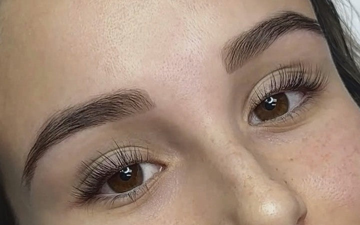 Close-up of shaped, tinted brows and lifted, curled lashes