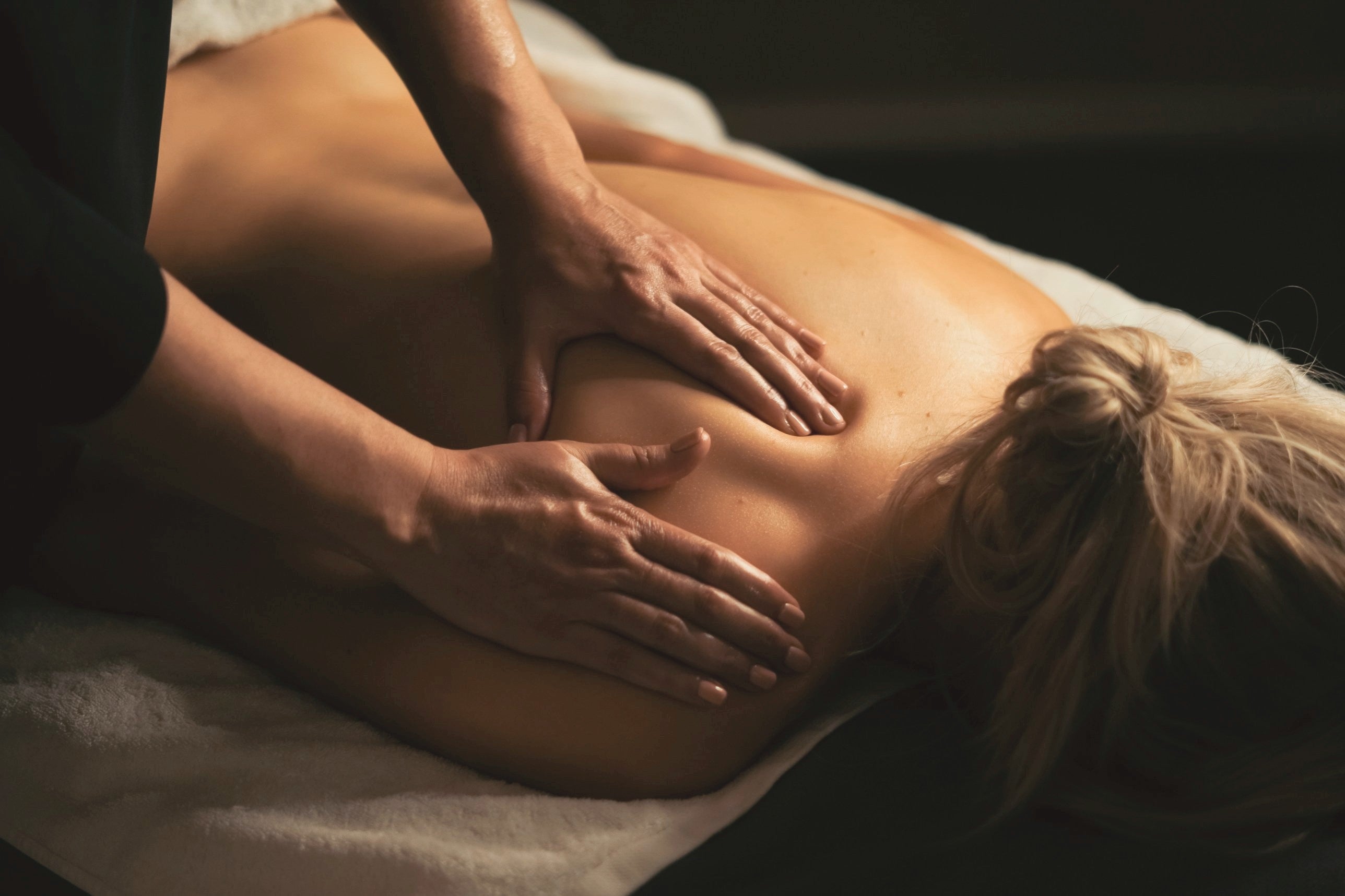 A therapist giving a relaxing shoulder massage in warm, low light