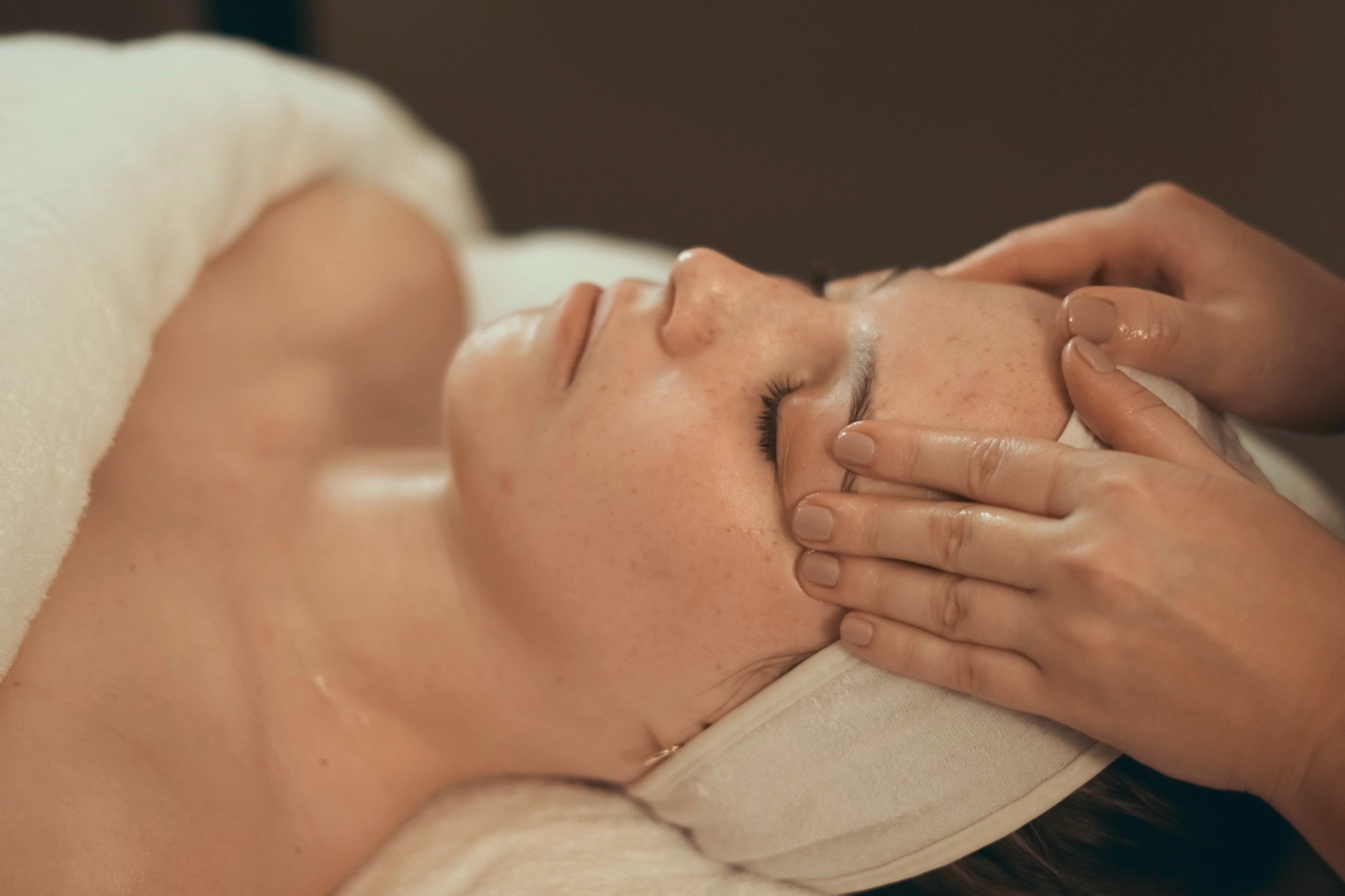 A therapist massaging a relaxed client's temples during a facial