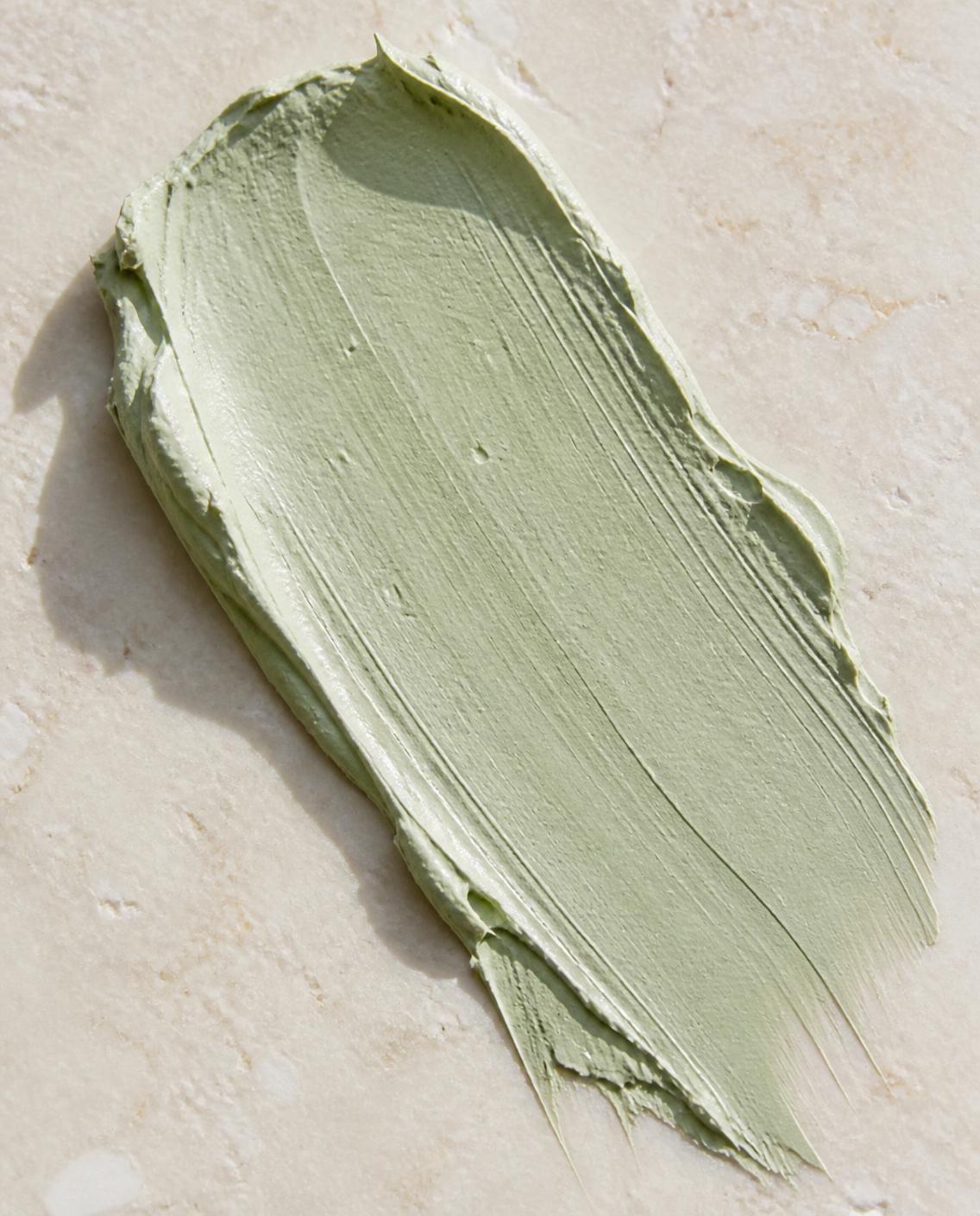 A swipe of sage clay mask on pale stone
